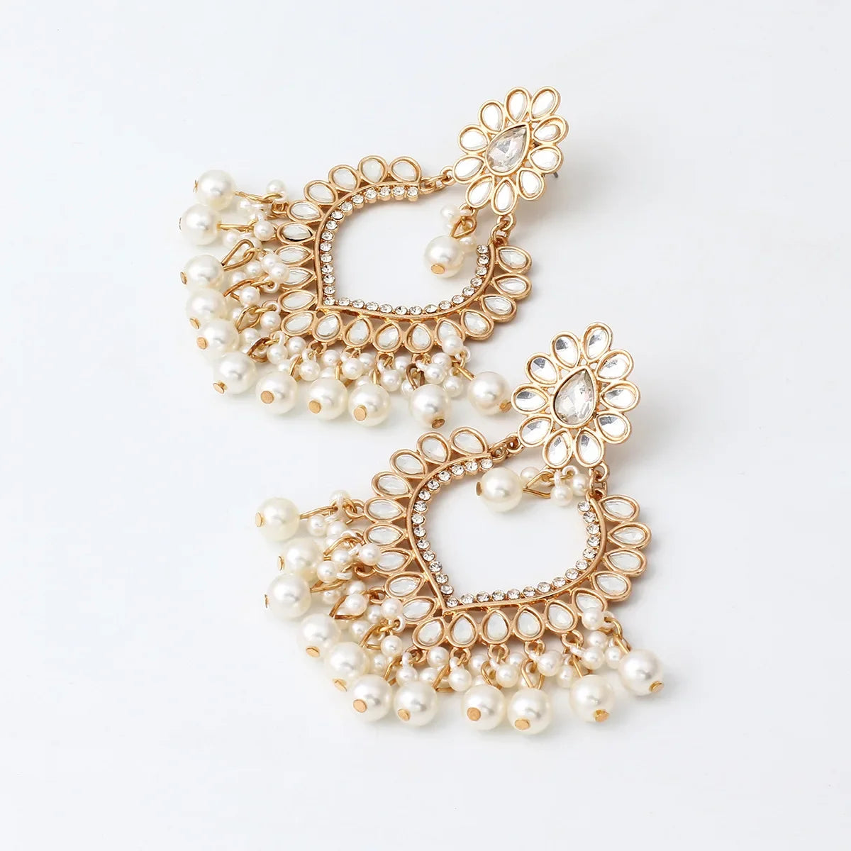 Pair of gold and pearl earrings on a light background
