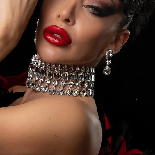 Close-up of a woman wearing a sparkling necklace and earrings with a dark background